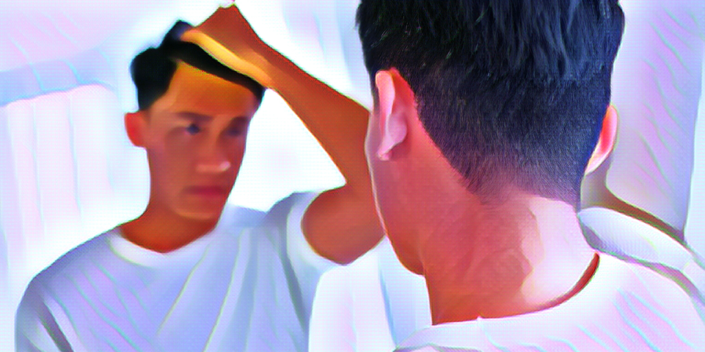 鏡の前で髪の毛を手で上げる男性